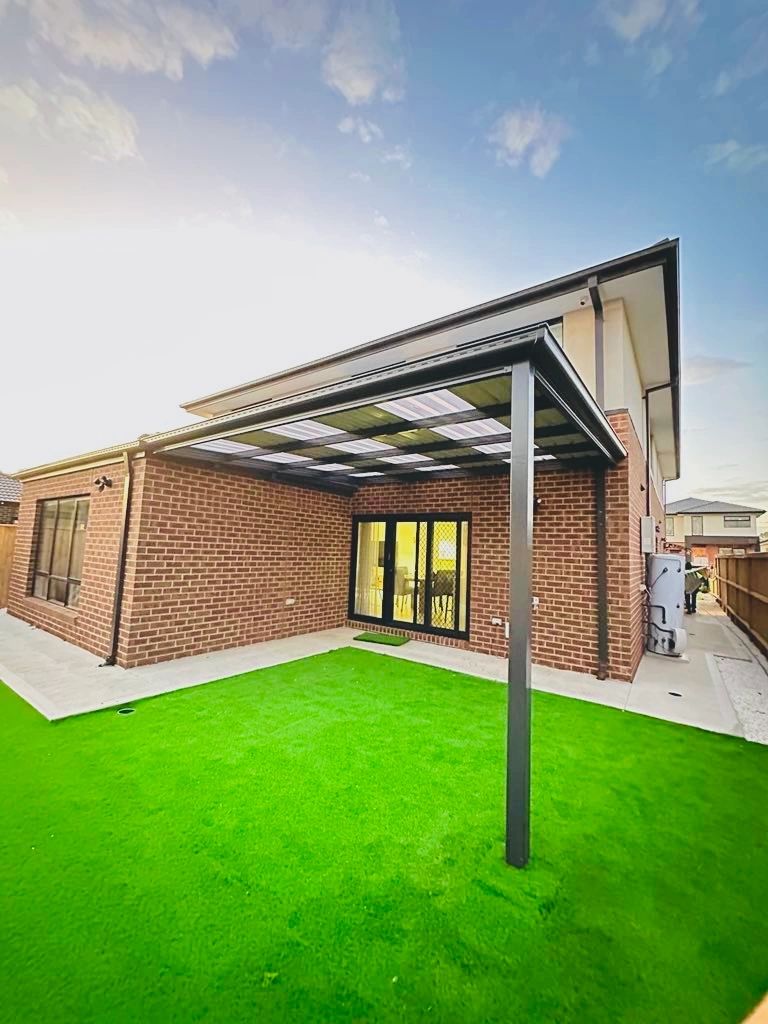Brick home with pergola and green lawn